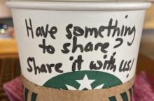  A starbucks coffee cup with the words "have something to share? Share it with us"